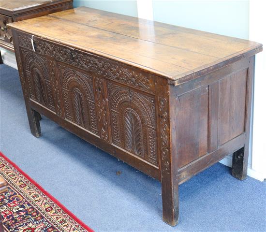 A 17th century carved oak panelled chest with planked top W.148cm